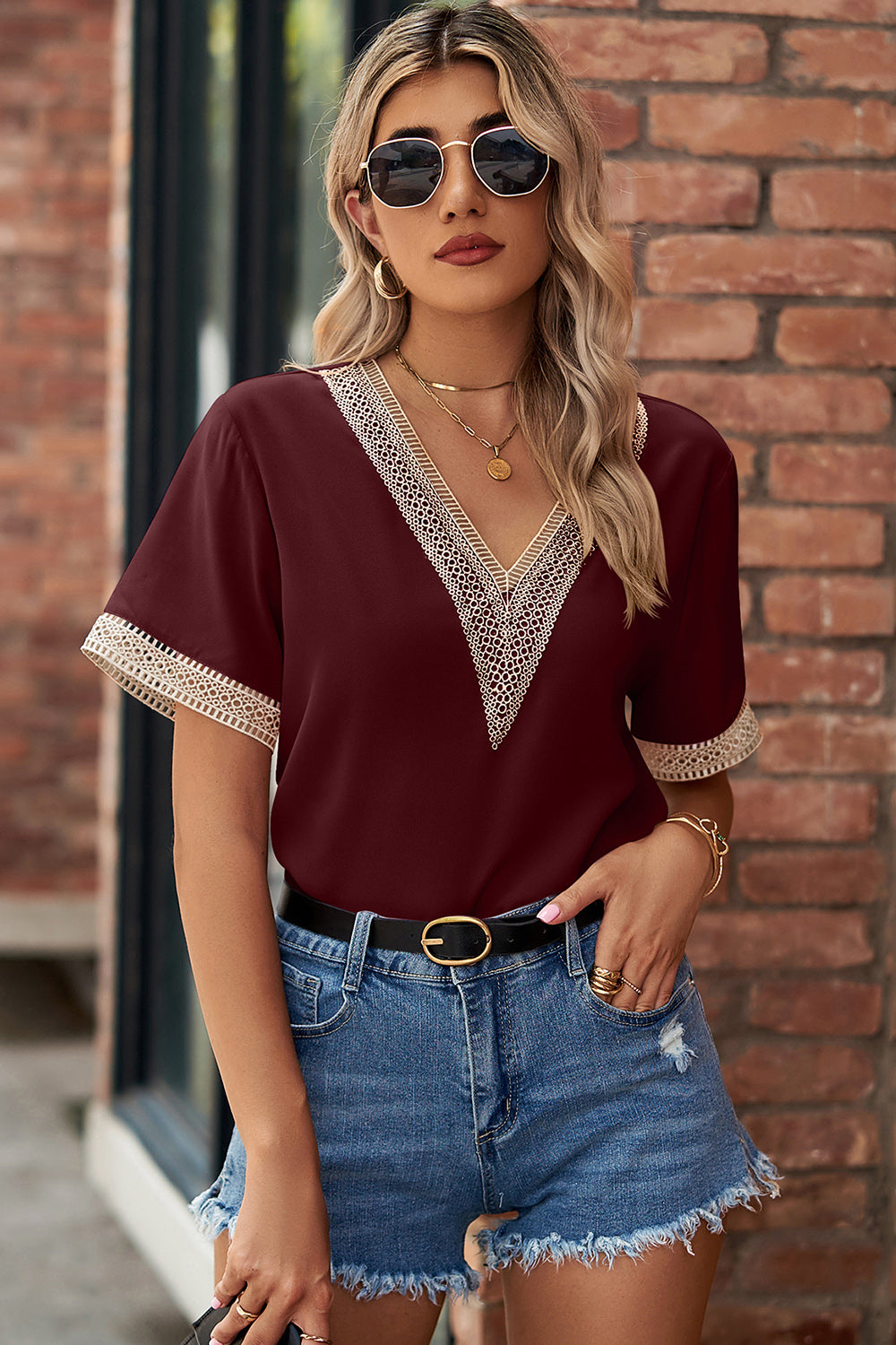 Burgundy V-neck blouse with lace trim detail and short sleeves.