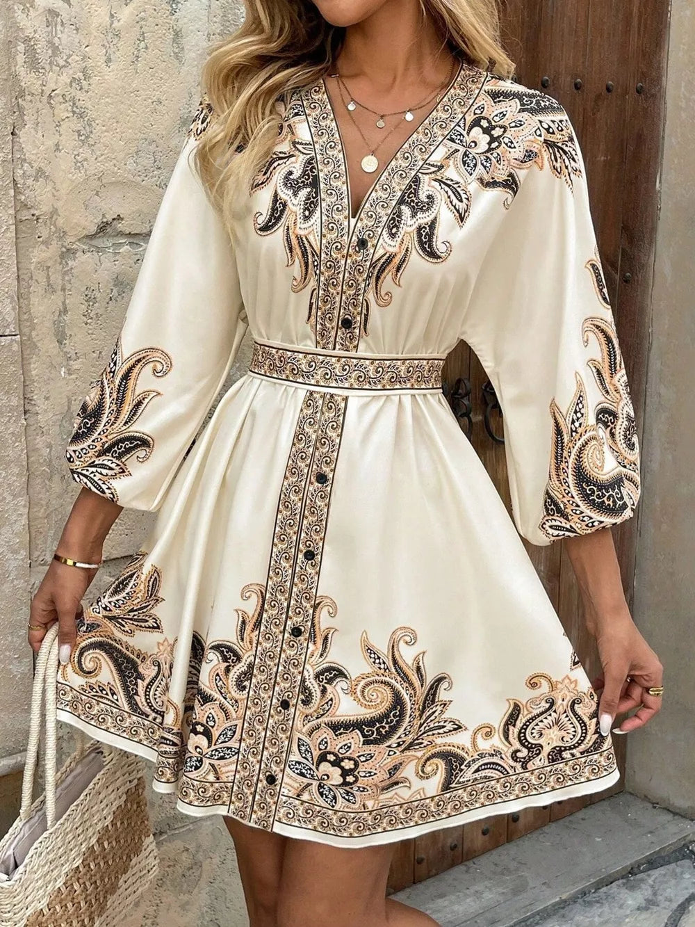 Vibrant paisley mini dress with V-neck, billowy sleeves, and waist tie in tan.