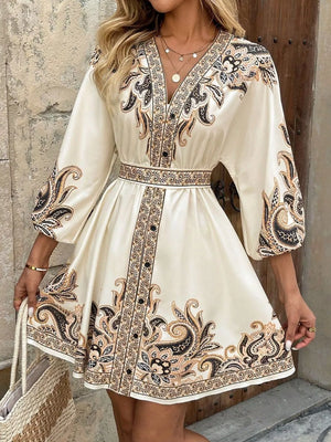 Vibrant paisley mini dress with V-neck, billowy sleeves, and waist tie in tan.