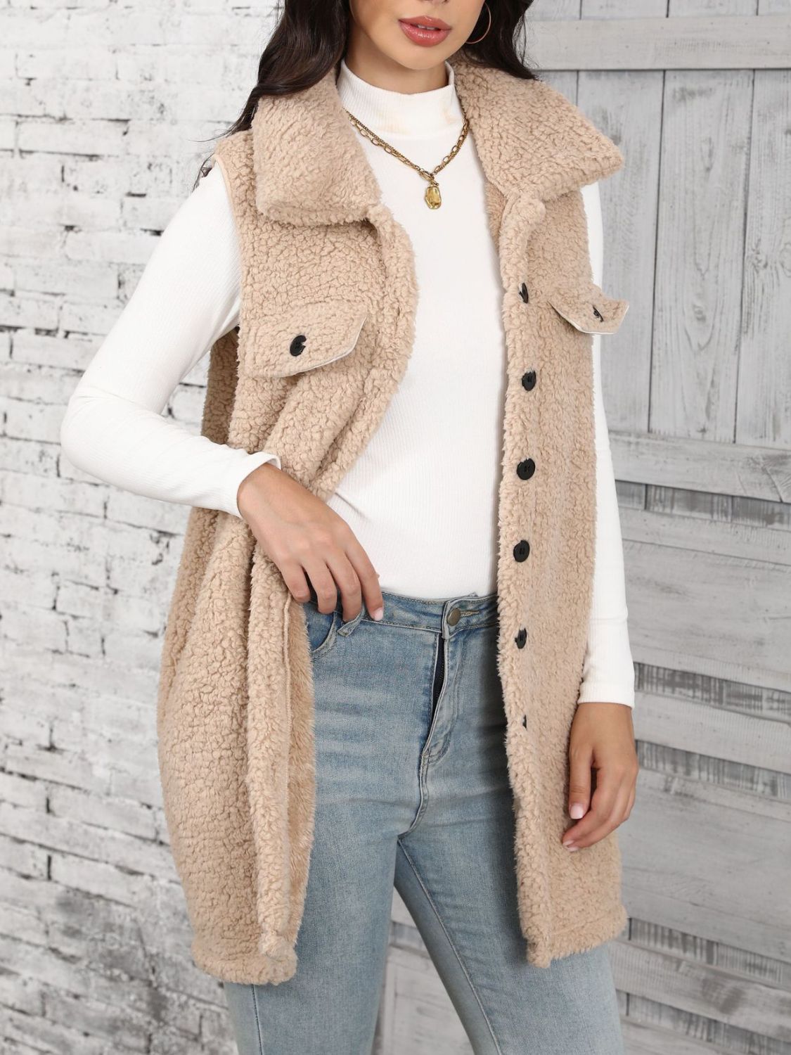 Tan sherpa utility vest with collar and button front, styled with a white turtleneck and jeans.