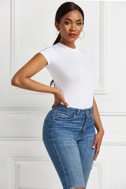 White crew neck short sleeve bodysuit with a sculpted fit, paired with blue denim jeans.