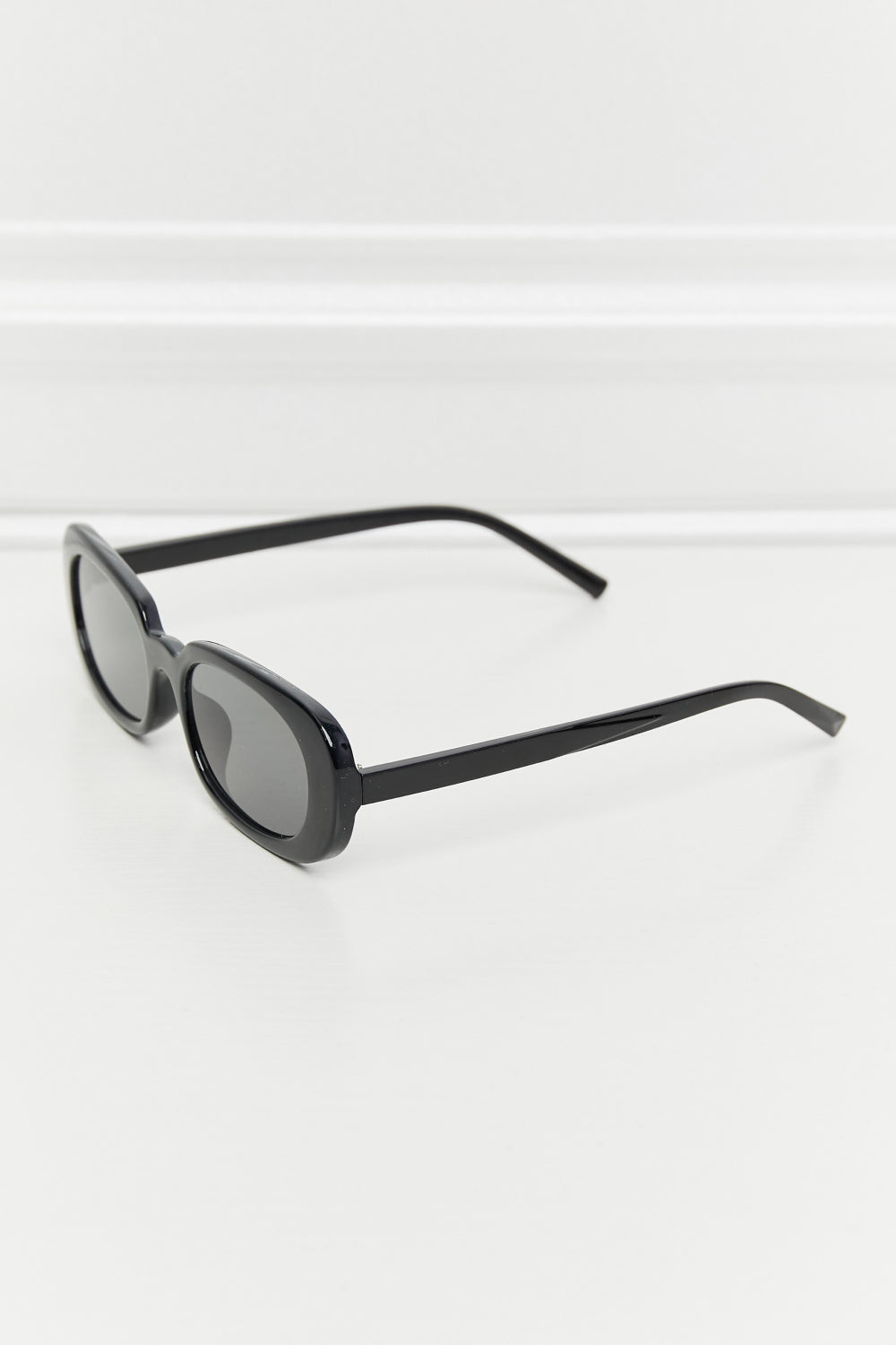 Black oval sunglasses with tortoiseshell sunset lenses and a sleek frame.