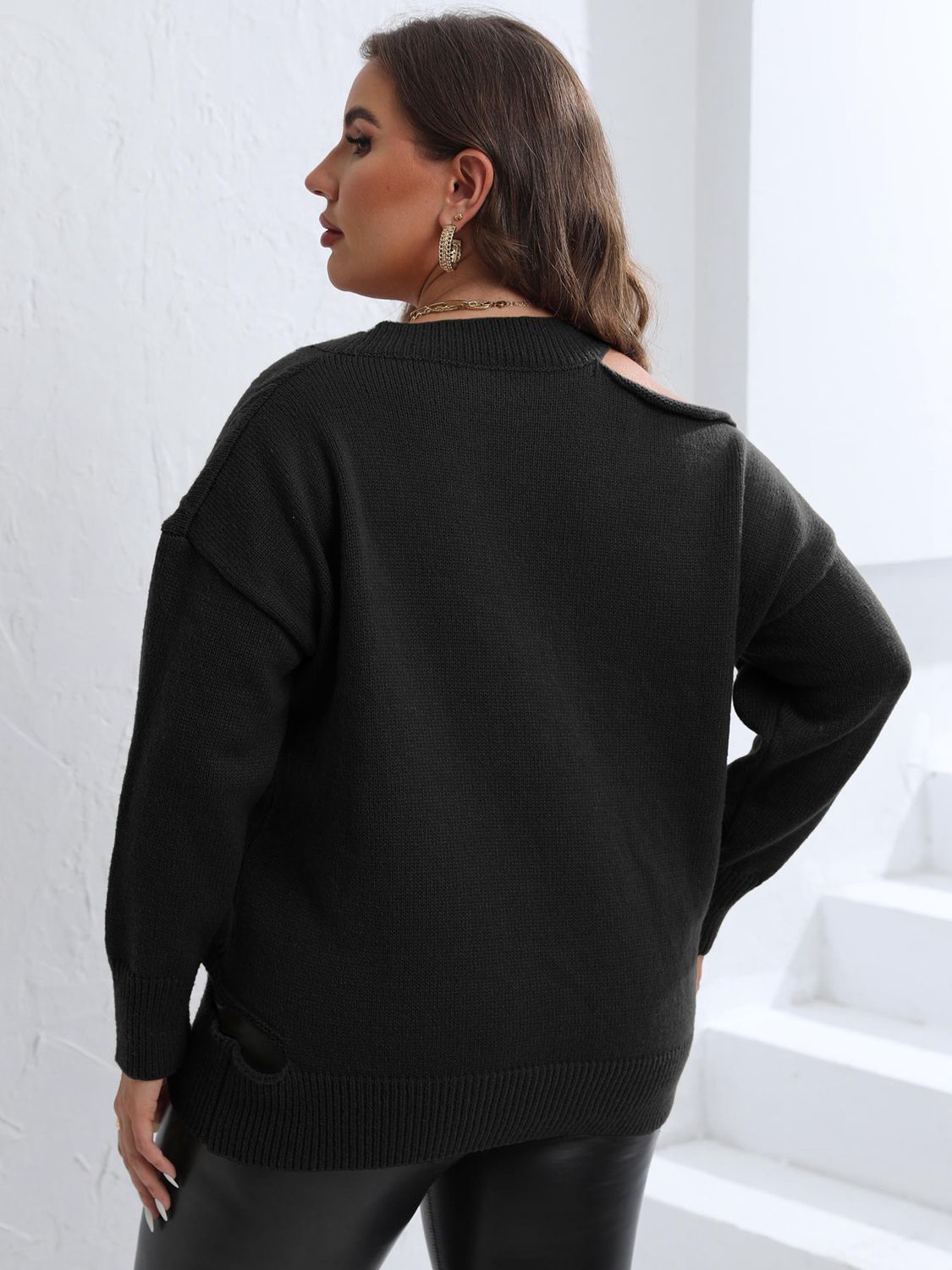 Black knit sweater with asymmetric shoulder detail and diamond pattern.