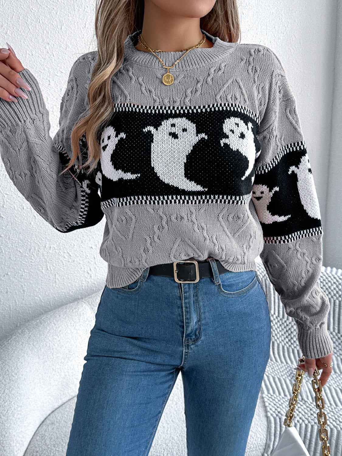 Gray cable knit crewneck sweater with a black and white ghost motif pattern.