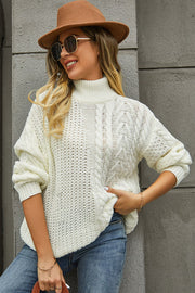 White cable-knit turtleneck sweater with voluminous silhouette and textured knit details.