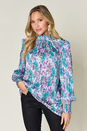 High neck abstract print blouse in red-violet and sky blue with smocked cuffs and collar.