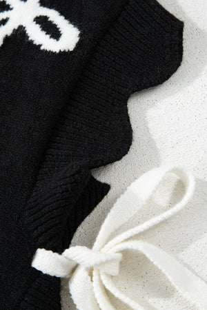 Black knit vest with white bow print and scalloped hem detail.