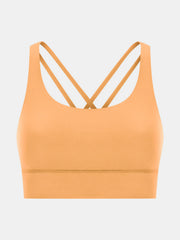 Performance bra in gold with crisscross straps and scoop neckline.