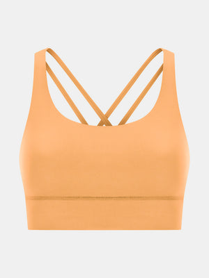 Performance bra in gold with crisscross straps and scoop neckline.