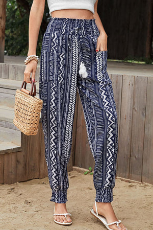 Dark blue geometric print drawstring trousers with tassel detail and elastic cuffs.