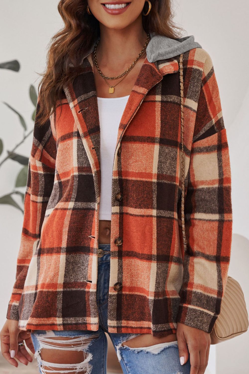Plaid hooded shacket in orange, tan, and brown with button front and relaxed fit.