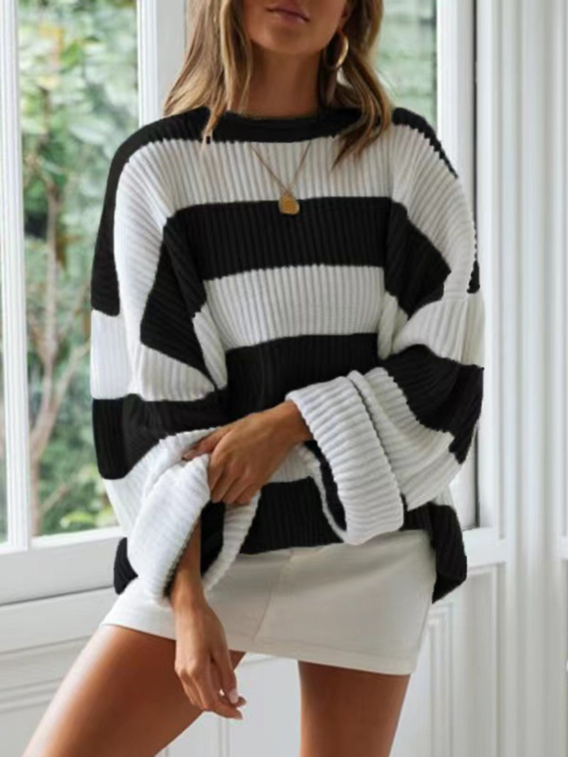 Black and white striped oversized knit sweater with wide sleeves and crew neck.