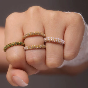 Pavé zirconia band rings in gold and dark green, plus a pearl ring.