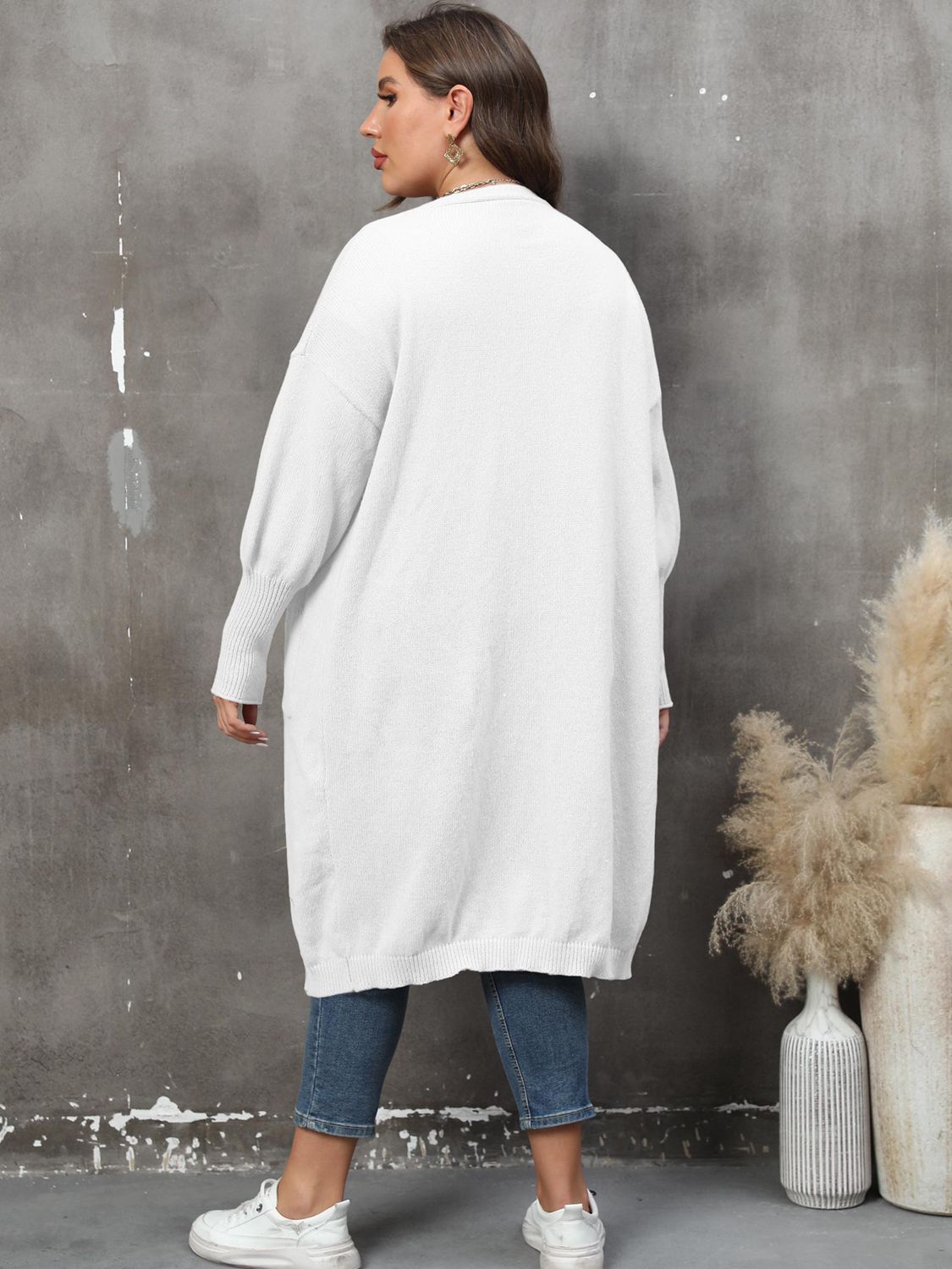 White oversized knit duster cardigan with patch pockets and ribbed cuffs.