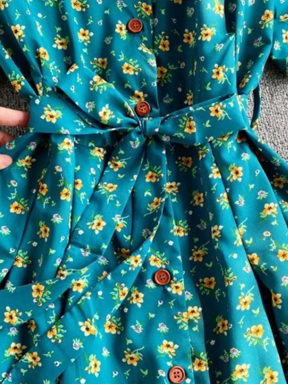 Light blue floral midi dress with V-neck, button front, and belted waist.