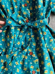 Light blue floral midi dress with V-neck, button front, and belted waist.