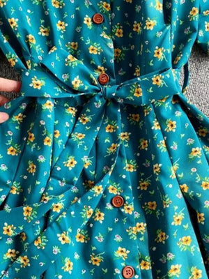 Light blue floral midi dress with V-neck, button front, and belted waist.