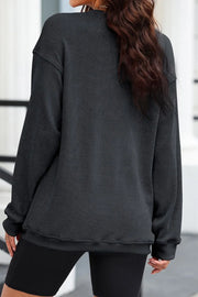 Dark gray ribbed sweatshirt with crewneck and long sleeves, styled with black shorts.