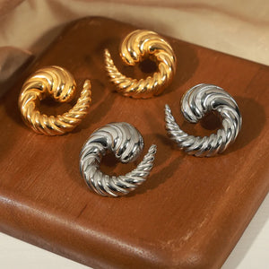 Sculptural swirl stud earrings in gold and silver with ribbed texture.