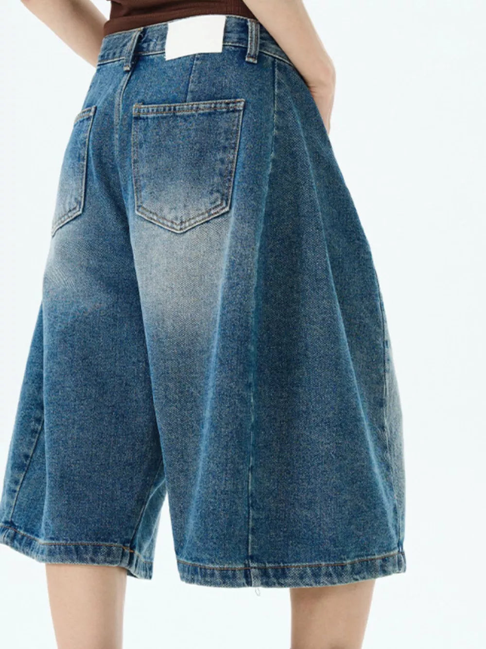 Men's blue denim wide-leg shorts with button fly and distressed details.