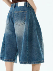 Men's blue denim wide-leg shorts with button fly and distressed details.