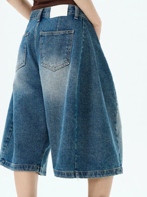 Men's blue denim wide-leg shorts with button fly and distressed details.