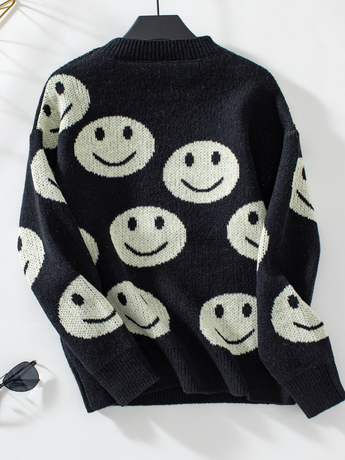 Black intarsia knit sweater with allover smiley face pattern and crewneck.