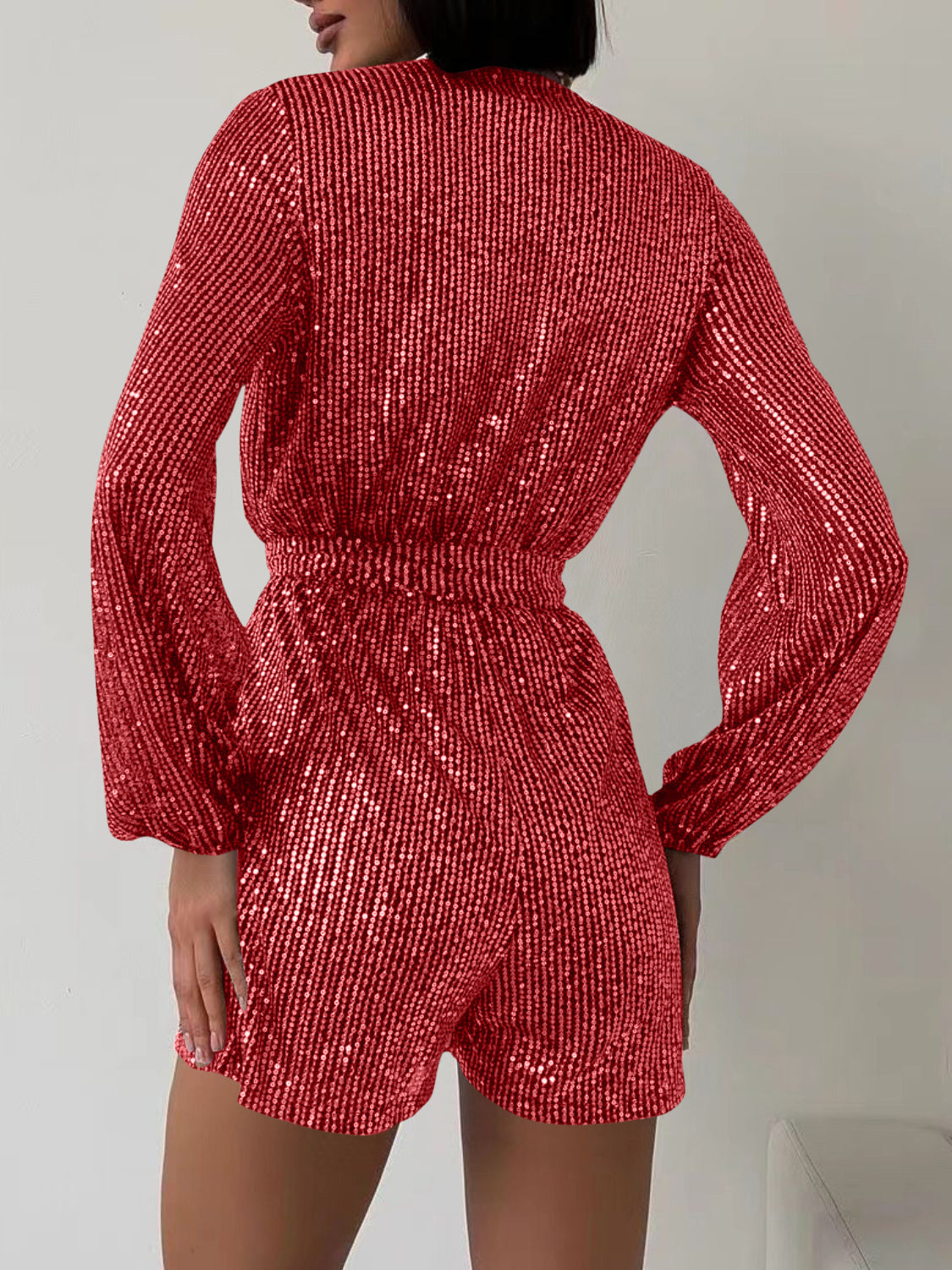 Sequin wrap romper in scarlet with blouson sleeves and elastic waist.