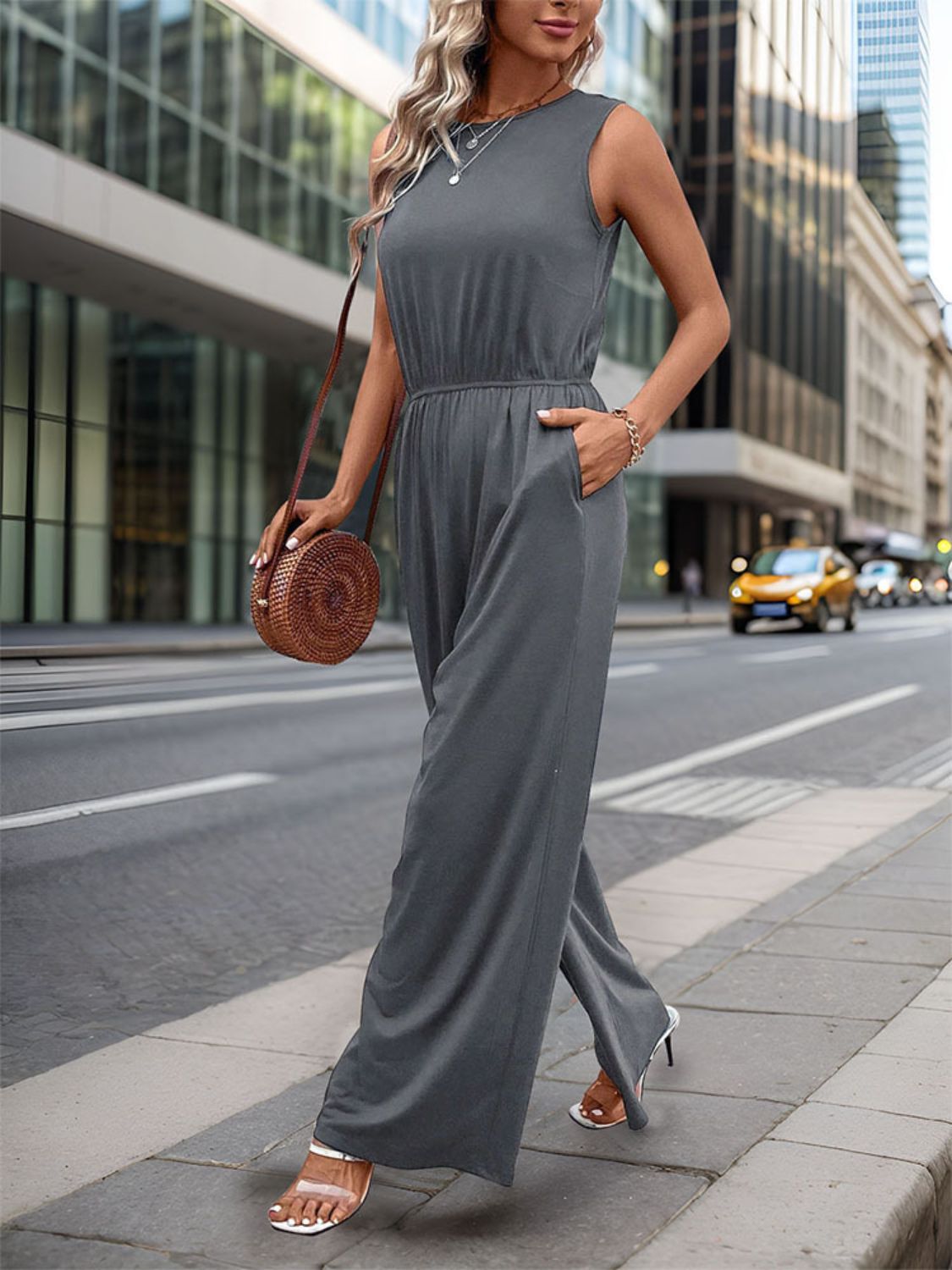 Sleeveless dark gray palazzo jumpsuit with gathered waist and pockets.