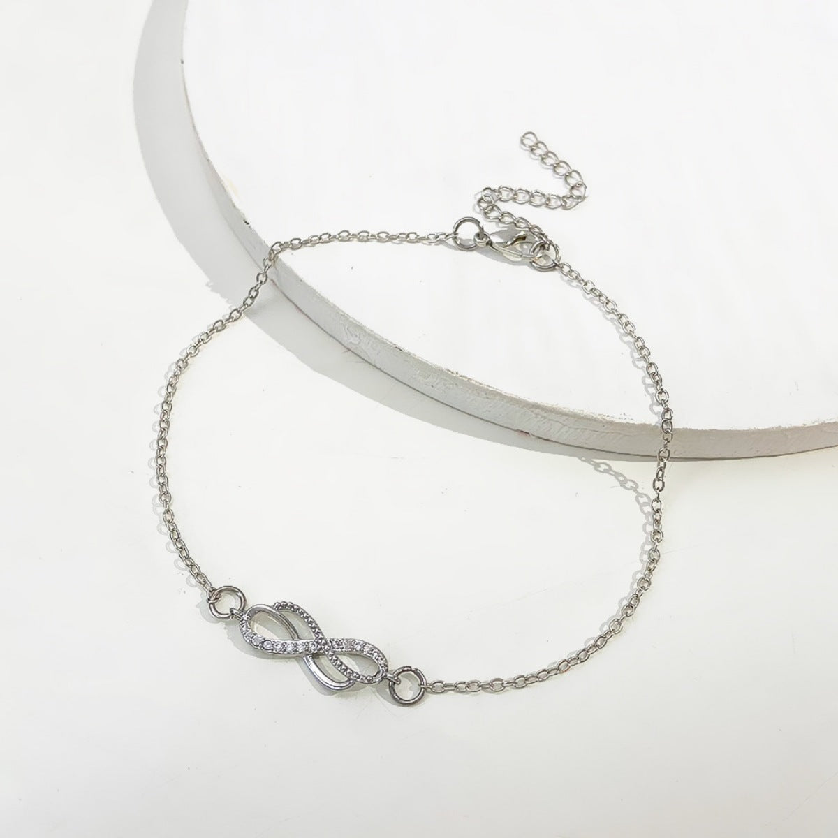 Silver infinity knot charm bracelet with adjustable chain and cubic zirconia accents