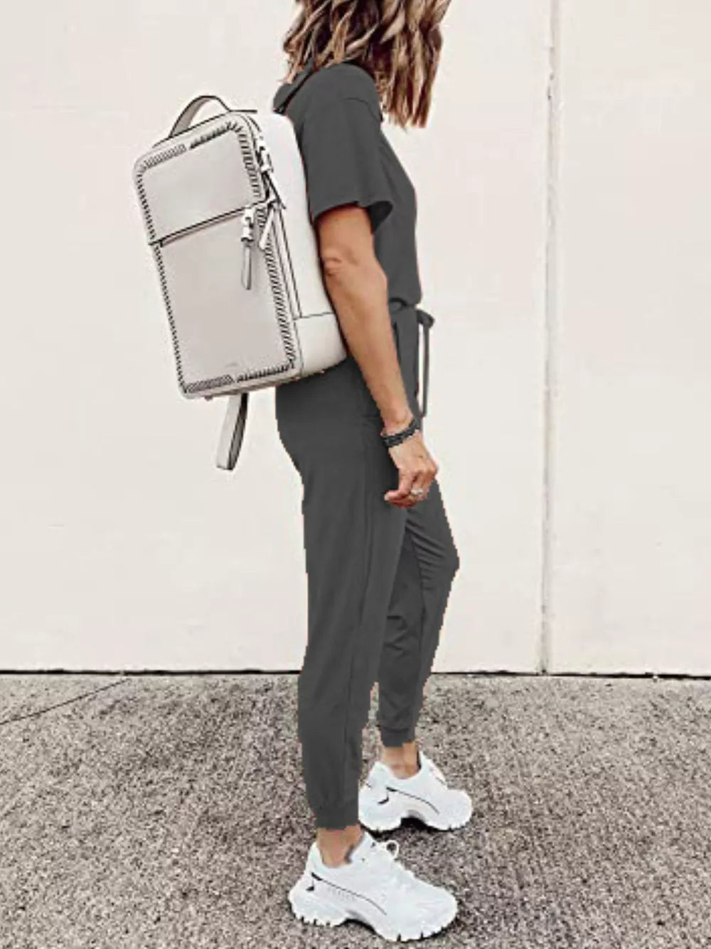 Dark Gray casual round neck top and jogger pants set with drawstring waist, worn with white sneakers and a backpack.