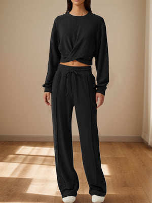 Black knit lounge set with a twisted front crop top and wide-leg pants with drawstring waist.