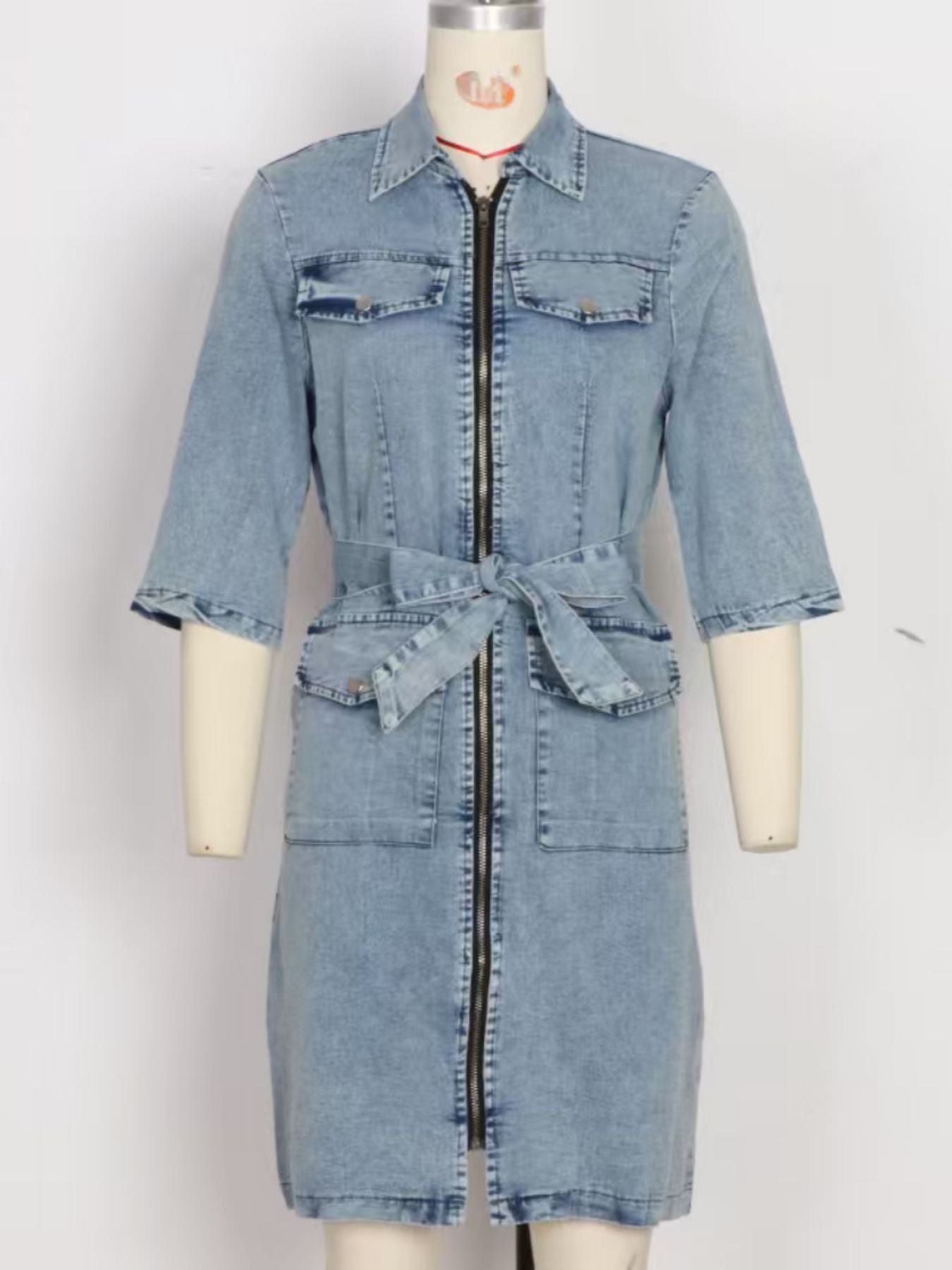 Light blue denim shirt dress with zipper front, tie waist, and chest pockets.