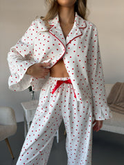 White cotton pajama set with red heart pattern, button front top, and red bow tie pants.