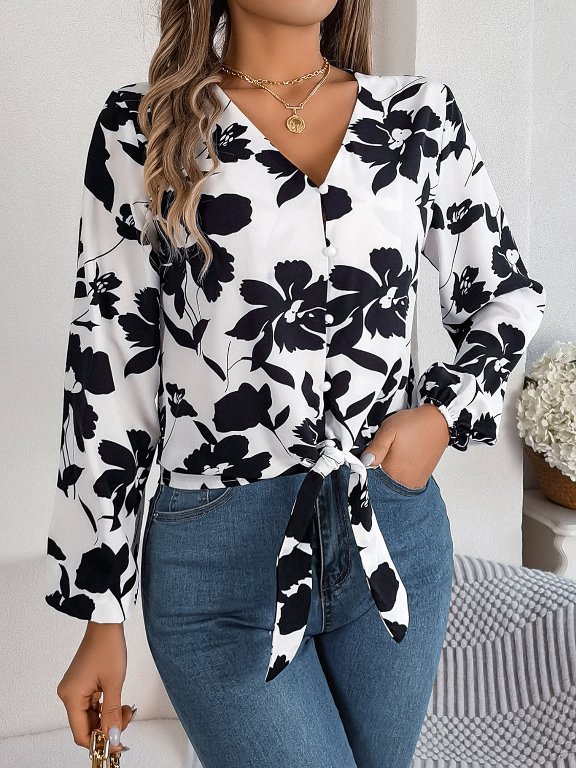 Floral knot-front blouse with ruffled cuffs in white with black print, V-neck, long sleeves.
