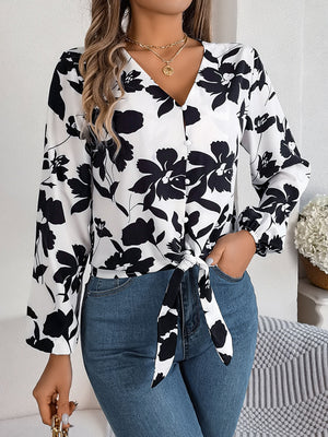 Floral knot-front blouse with ruffled cuffs in white with black print, V-neck, long sleeves.