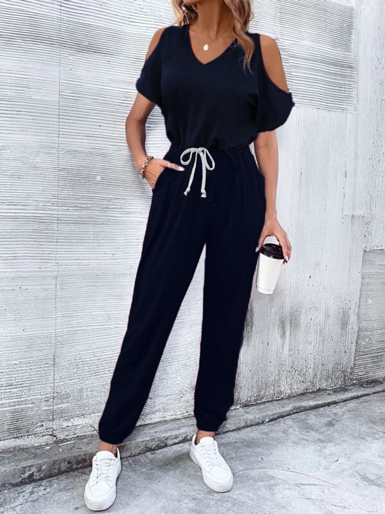 Dark blue cold-shoulder jumpsuit with drawstring waist and cuffed ankles.