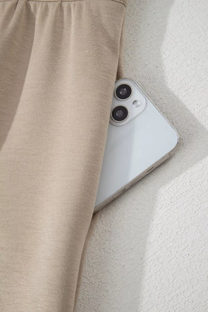 Chic collared romper in beige with a functional pocket holding a phone.