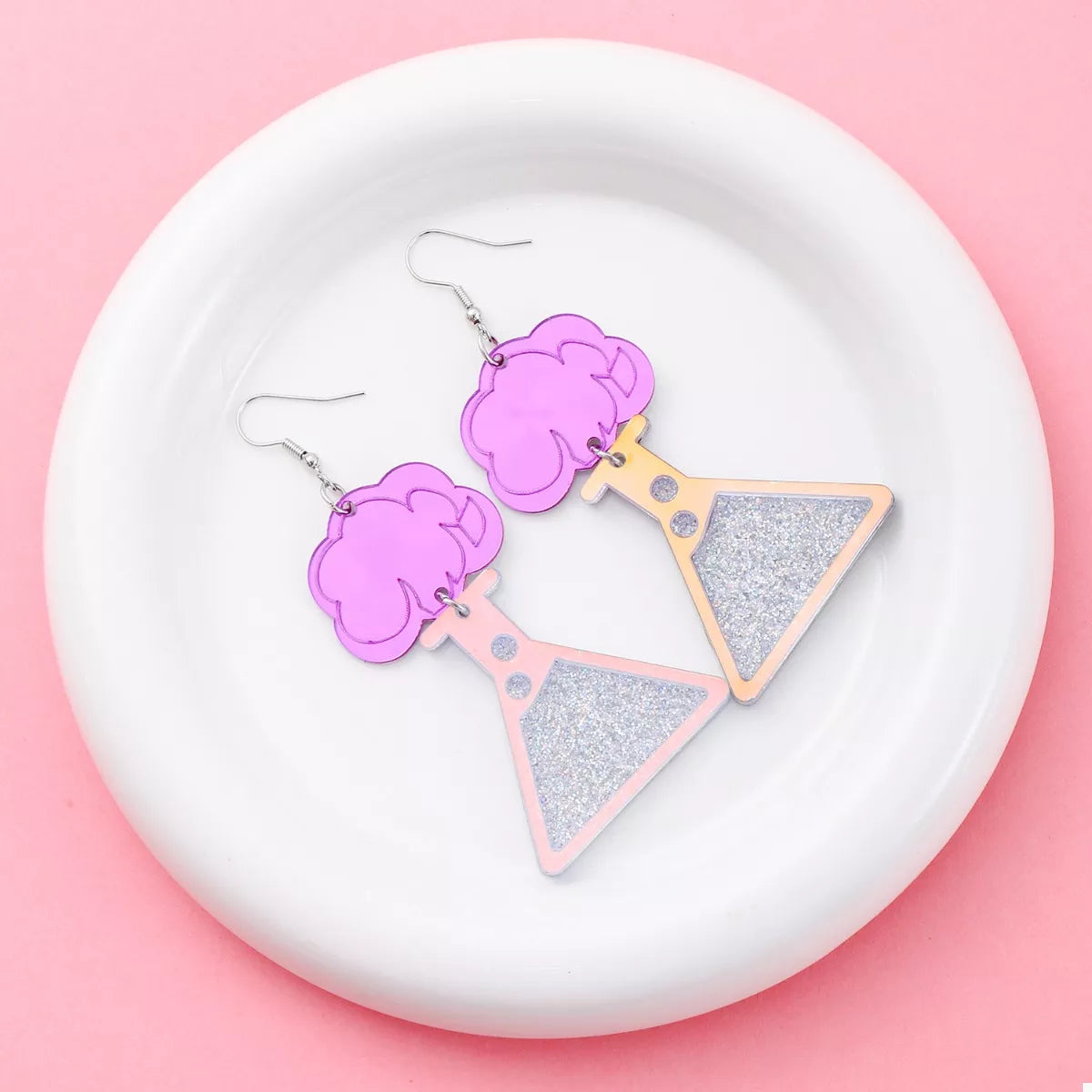 Fuchsia pink acrylic dangle earrings shaped like science beakers with glitter accents.