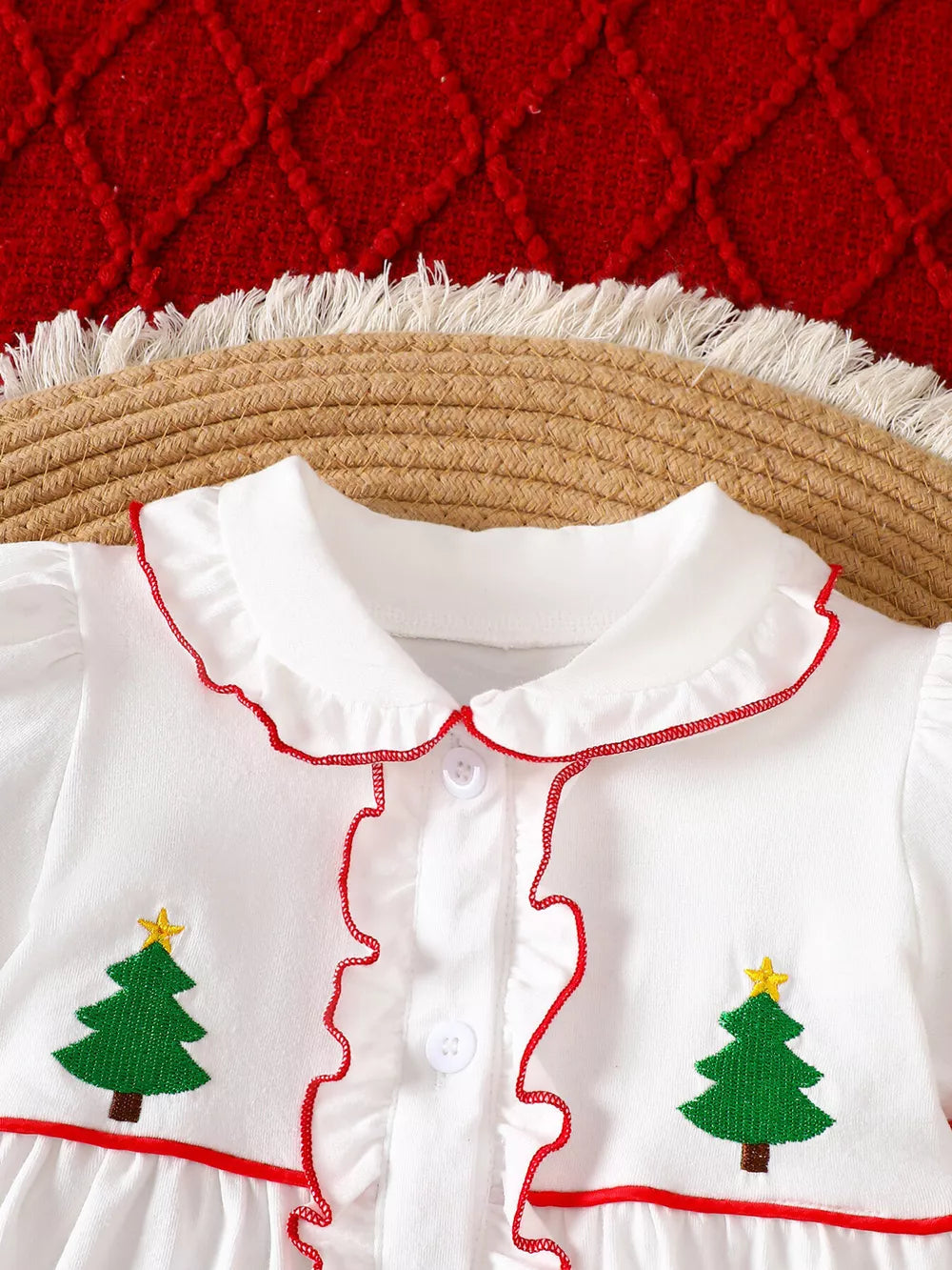 White baby dress with embroidered Christmas trees, red trim, and ruffles.