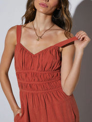 Orange-red tie-strap bodice wide-leg jumpsuit with smocked waist and v-neckline.