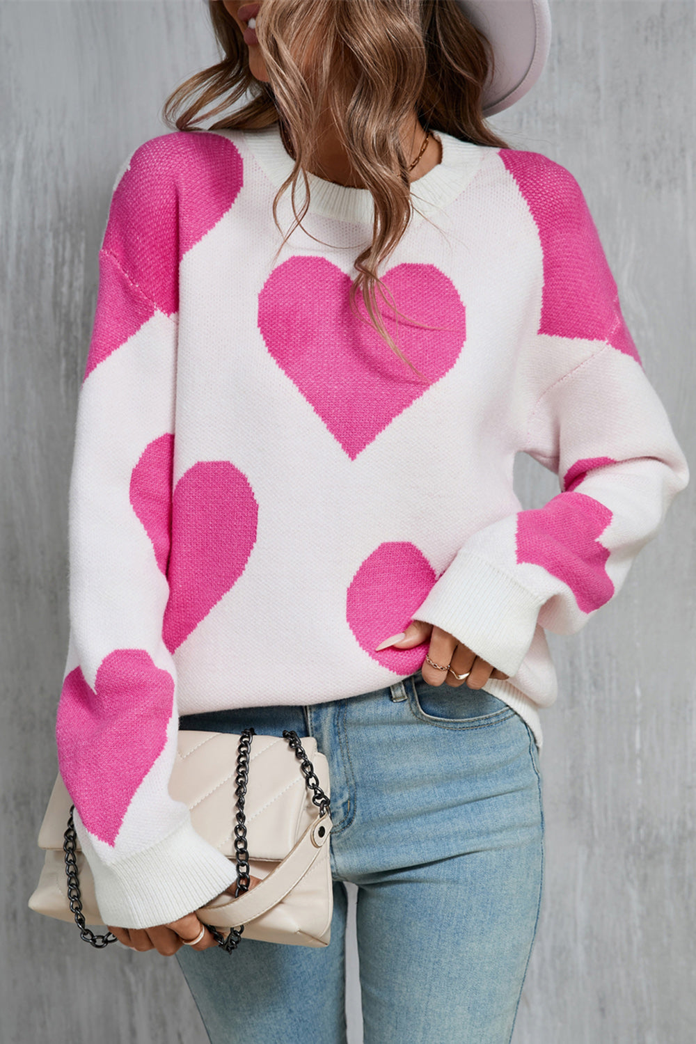White knit sweater with fuchsia pink heart pattern, crew neck, long sleeves.