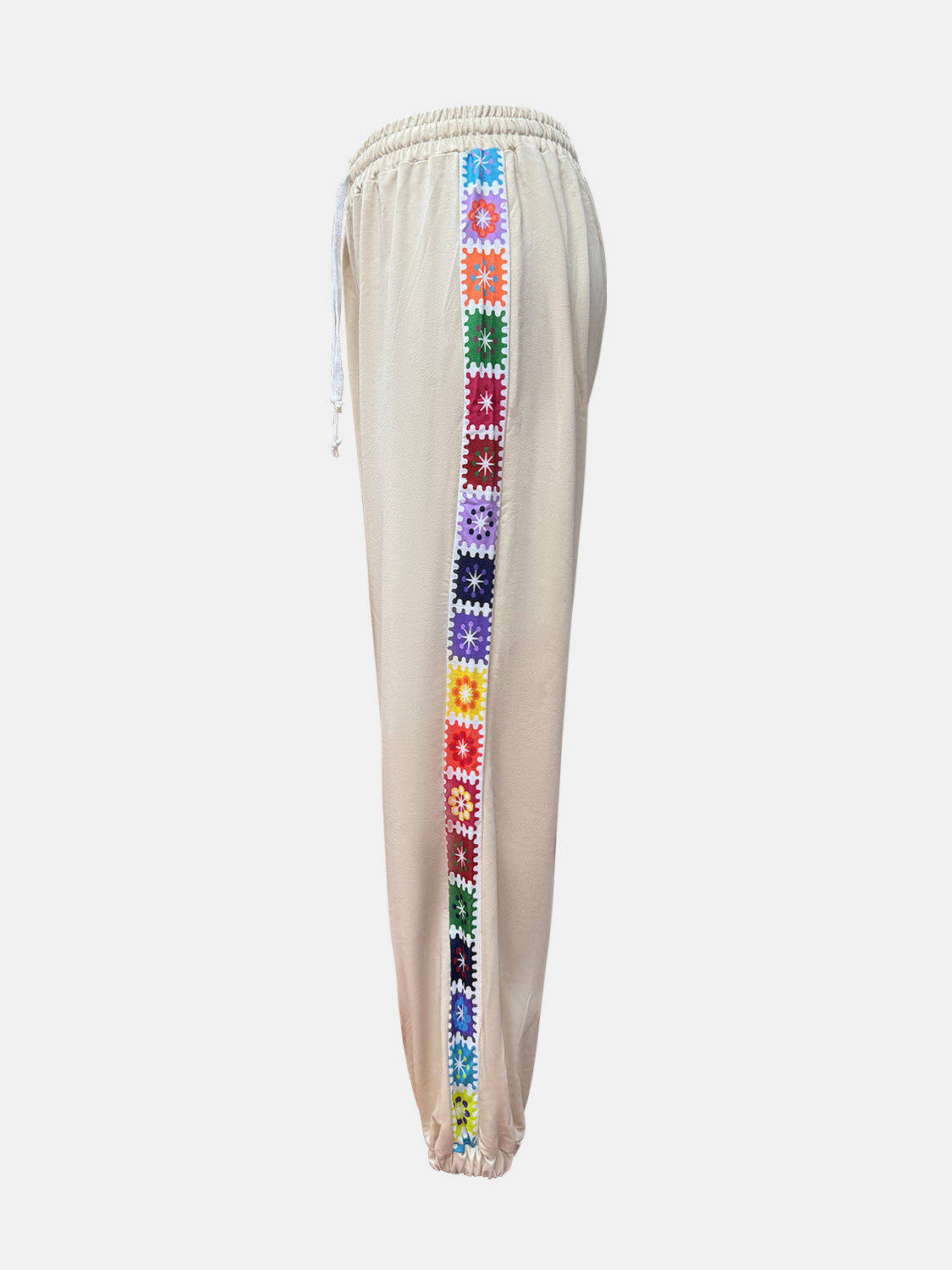 Tan jogger pants with colorful embroidered stripe detail down the side.