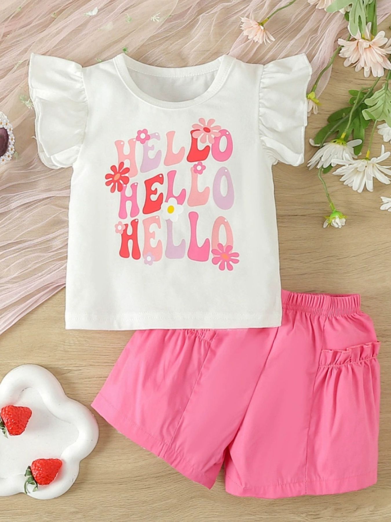 Baby girl's white ruffle sleeve top with "Hello" graphic and bright pink shorts.