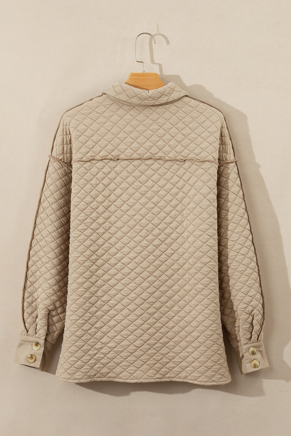 Diamond quilted beige oversized button-up jacket with raw edge detail and button cuffs.