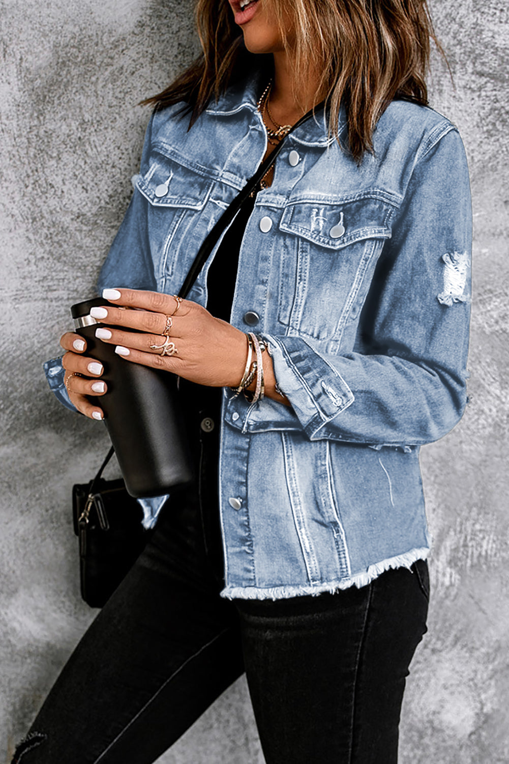 Blue distressed denim trucker jacket with frayed hem and distressed details.