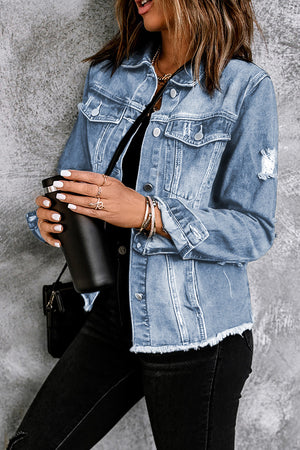 Blue distressed denim trucker jacket with frayed hem and distressed details.