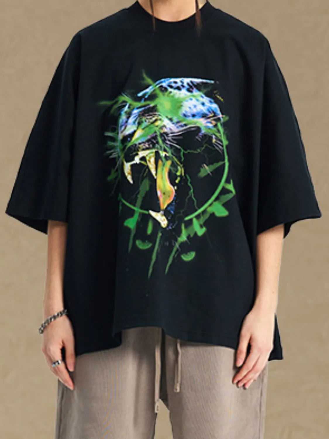 Black oversized tee with a bold graphic print of a roaring leopard with green lightning accents.