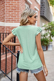 Light green eyelet blouse with lace trim and flutter sleeves, styled with denim shorts.