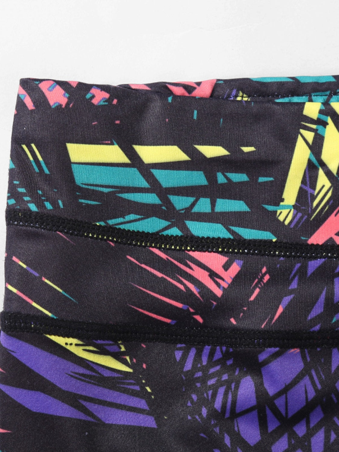 Performance leggings with a black background and a colorful abstract geometric palm leaf print.